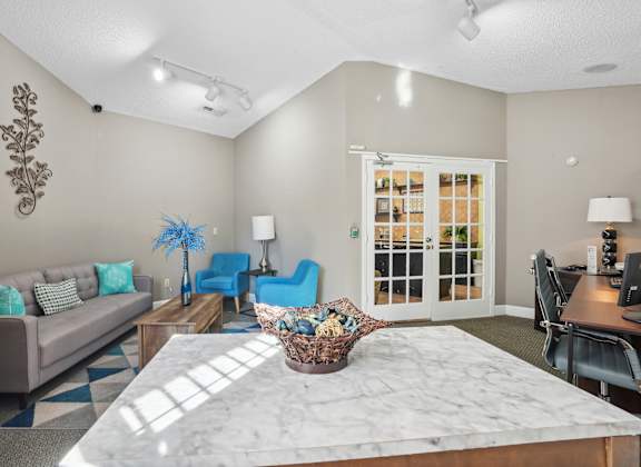 A living room with a grey couch, blue chairs, and a marble table.