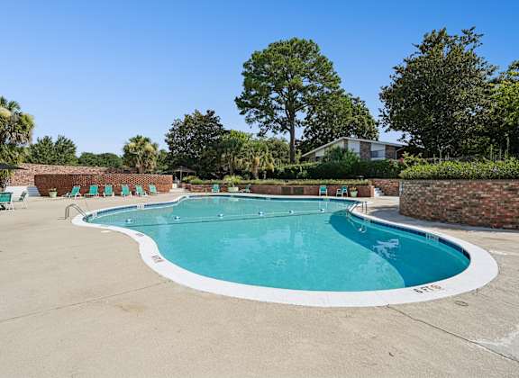 A large outdoor swimming pool with a white border and a white concrete edge.