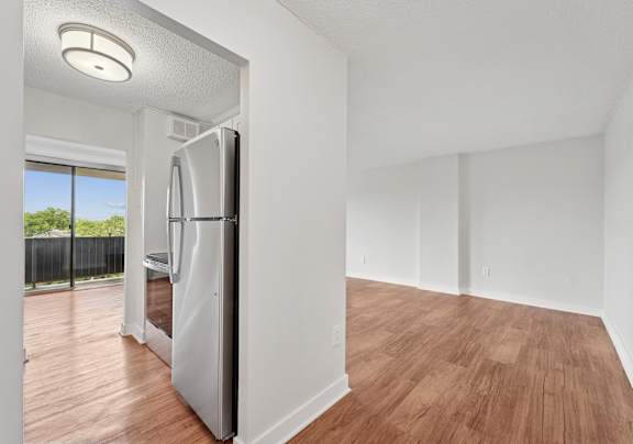A modern kitchen with a refrigerator and wooden flooring.