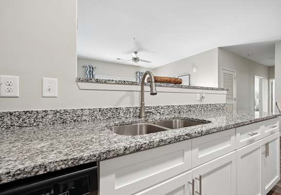 A kitchen with a granite countertop and a stainless steel sink.