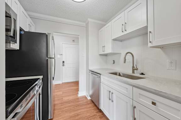 A kitchen with white cabinets and a black refrigerator.