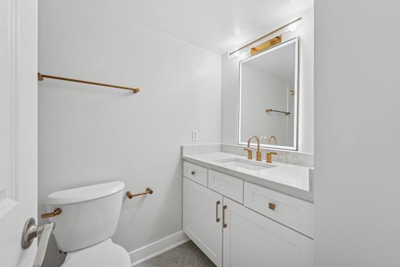 A white bathroom with a toilet, sink and mirror.