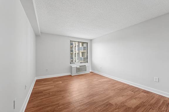 A room with wooden flooring and a window with a view of a cityscape.