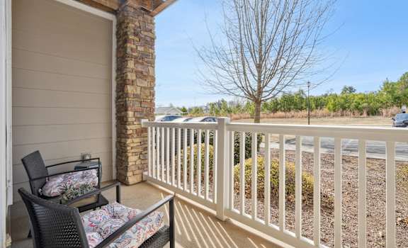 A balcony with a white railing and a chair with a floral cushion.