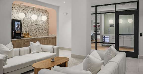 A white couch with a wooden table in front of a wall with a patterned wallpaper.