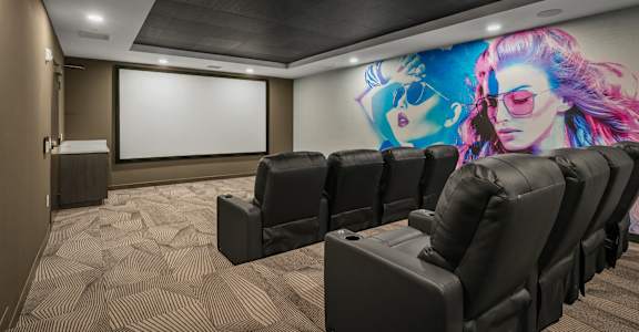 A movie theater with black chairs and a large screen.