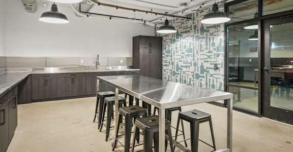 A kitchen with a table and stools in the foreground and a glass wall in the background.