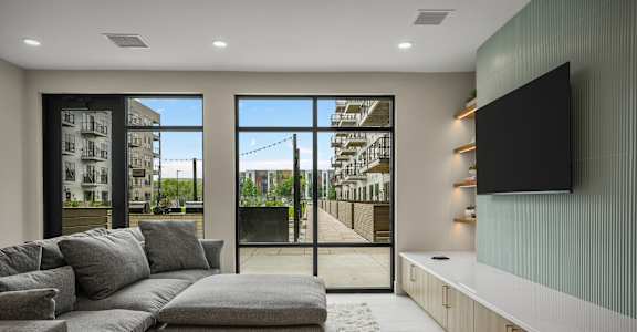 A modern living room with a grey sofa and a flat screen TV mounted on the wall.
