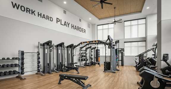 A gym with a variety of equipment and a ceiling fan.