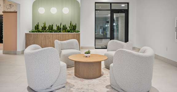 A modern waiting room with grey chairs and a wooden table.