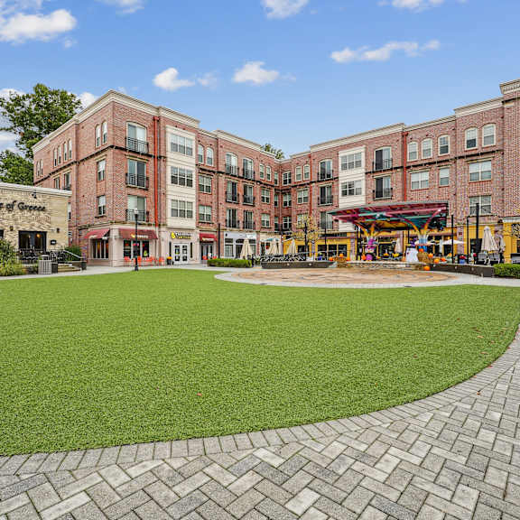 A large grassy area in front of a building with a brick walkway.