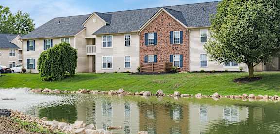 an apartment building with a pond in front of it