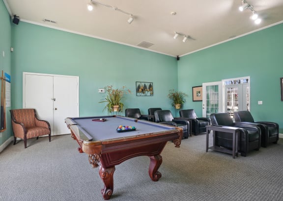 a game room with a pool table and leather furniture