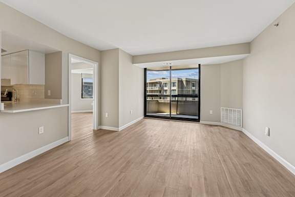A spacious living room with hardwood floors and a view of a building outside the window.