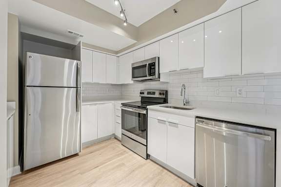 A modern kitchen with white cabinets and stainless steel appliances.
