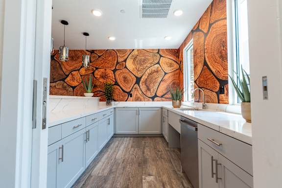 A kitchen with a wood grain wallpaper and white cabinets.