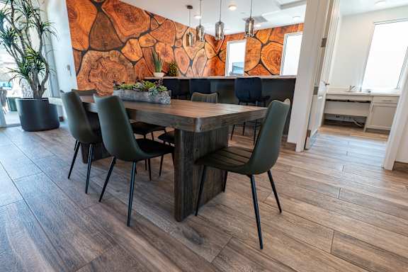A wooden table with green chairs in front of a wooden wall.