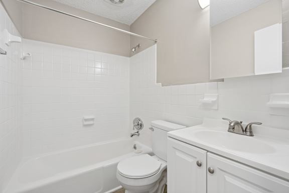 A white bathroom with a toilet, sink, and bathtub.