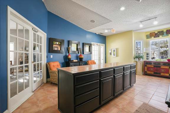 A modern kitchen with a marble island and a large painting on the wall.