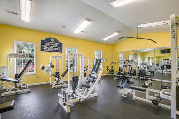 A gym with exercise bikes and a view of a building outside the window.
