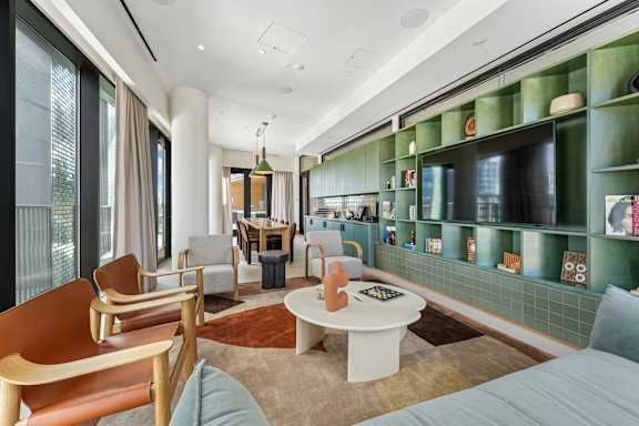 A living room with a white couch and a green shelf.