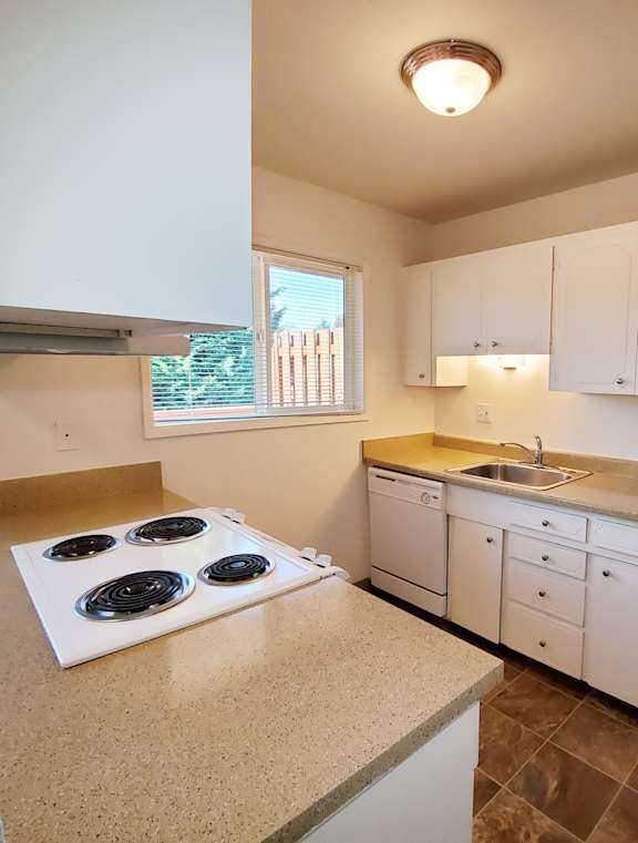 A kitchen with white cabinets and a white stove top oven.