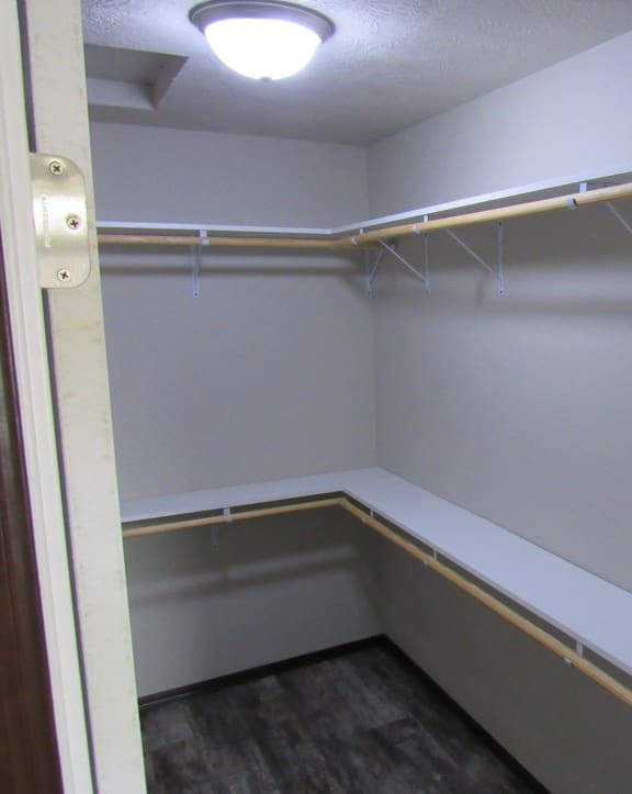 a walk in closet with shelves and a light
