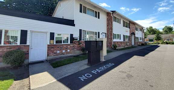 A white building with a black "NO PARKING" sign painted on the pavement in front of it.