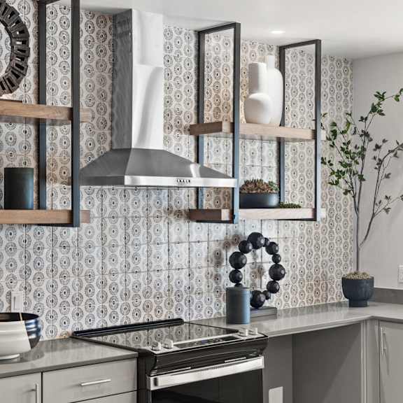 a kitchen with a stove and shelves on the wall