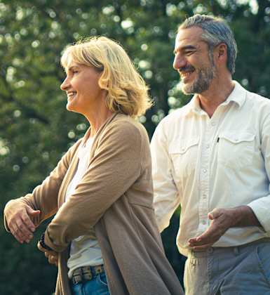 A man and a woman are standing in a park.