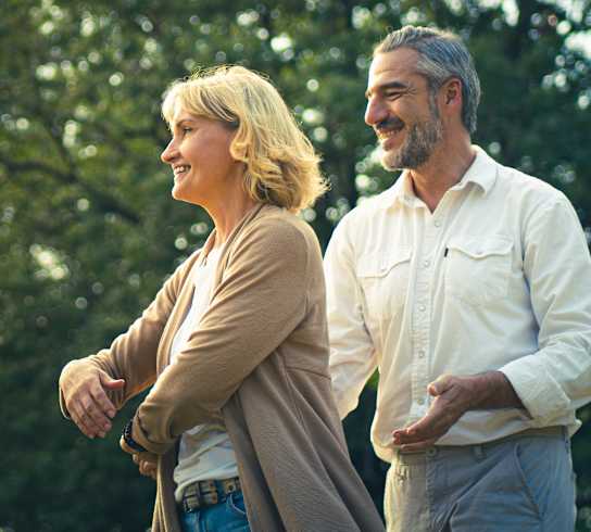 A man and a woman are standing in a park.