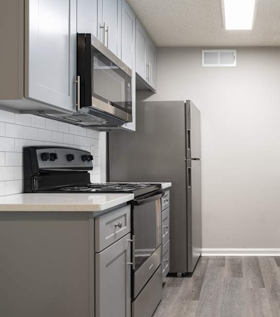 A kitchen with a refrigerator, stove, and microwave.