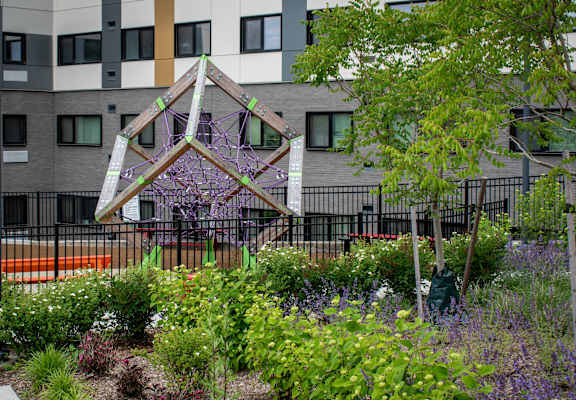 a garden with flowers and trees in front of a building