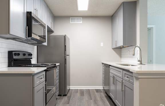 A kitchen with a refrigerator, stove, and microwave.