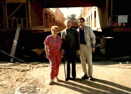 two men and a woman standing in front of a building