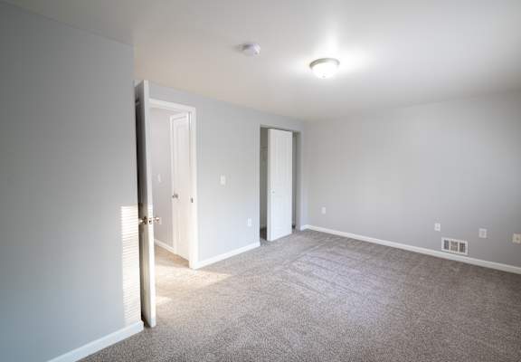 An empty living room with white doors and a carpeted floor at Willowbrooke Apartments, Brockport, New York, 14420