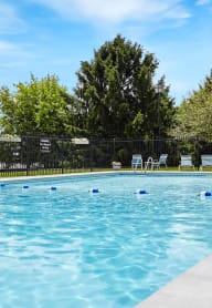 a swimming pool with a fence and trees in the background