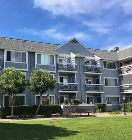 A large grey apartment building with a balcony on the second floor.