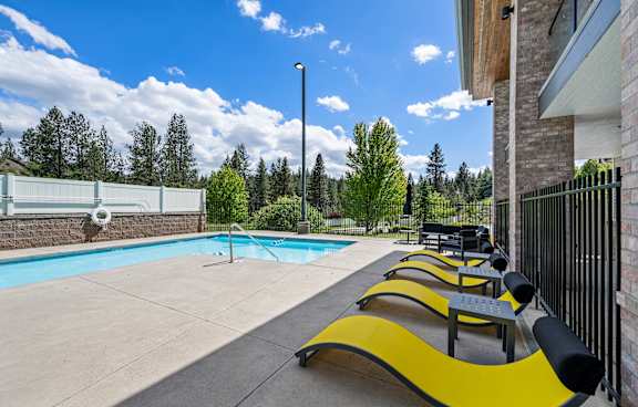 A large swimming pool in front of a building with a white fence on the right side.