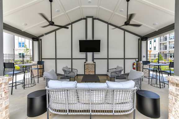 A patio with a white couch and a television on the wall.