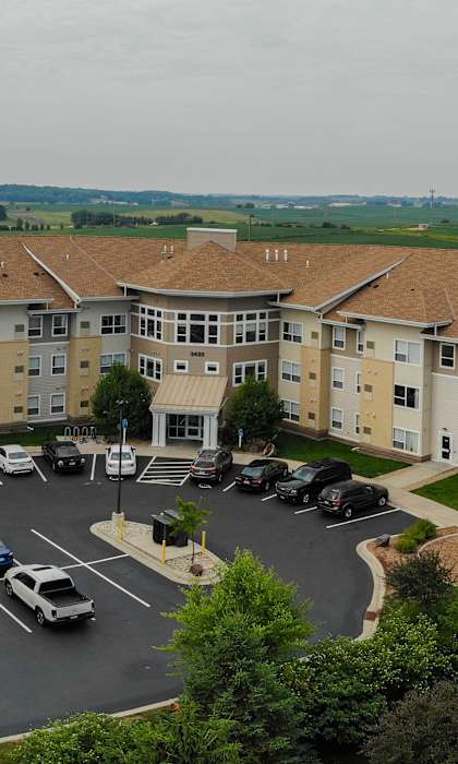 A parking lot in front of a large apartment building.