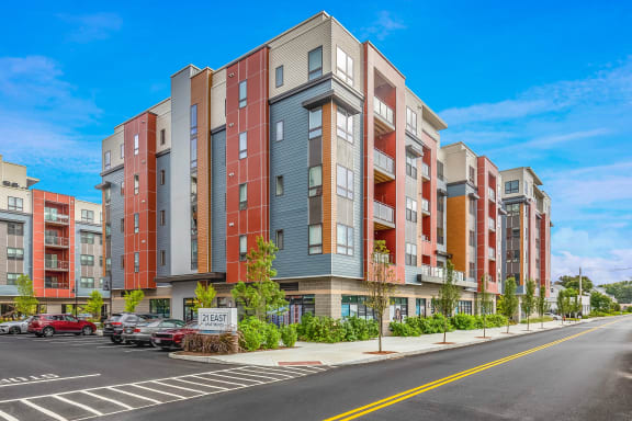 a street view of an apartment building with cars parked in front of it