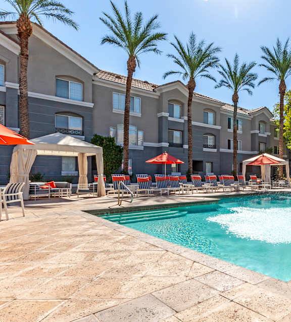 A swimming pool surrounded by palm trees and lounge chairs.