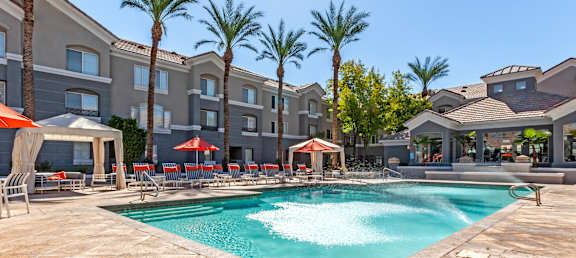A swimming pool surrounded by palm trees and lounge chairs.