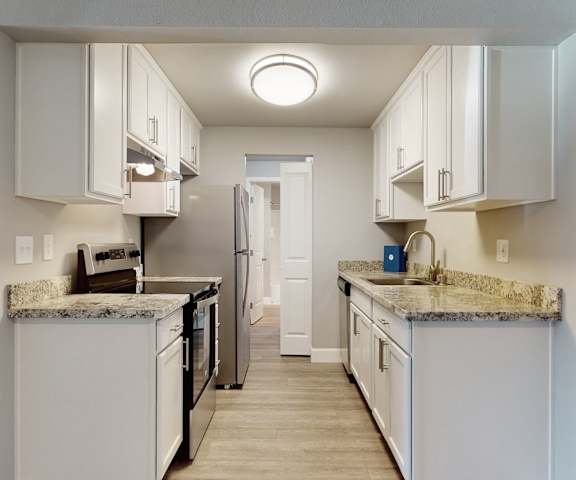 A kitchen with white cabinets and granite countertops at A'Cappella. 