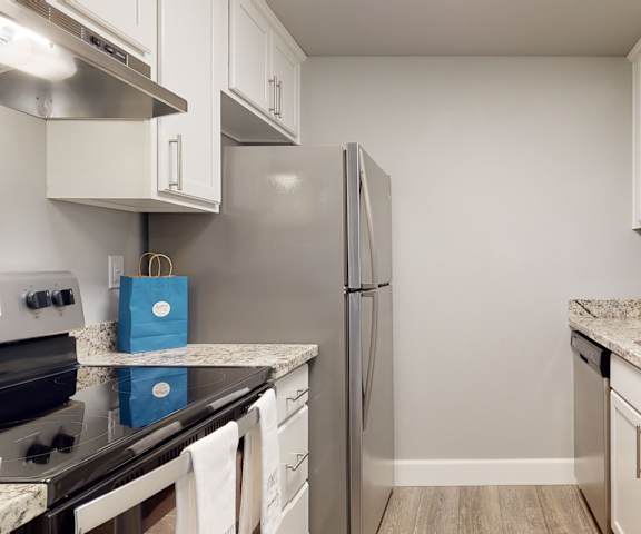 Kitchen at A'Cappella with grey countertops, white cabinets, and stainless-steel appliances. 