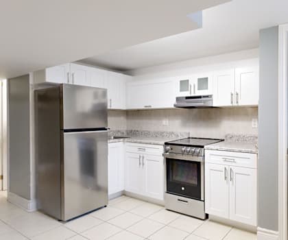 A kitchen with white cabinets and a stainless steel refrigerator.
