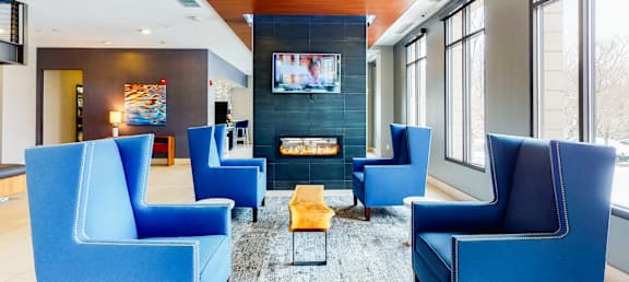 A living room with blue chairs and a fireplace.