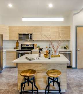 A kitchen with a white counter top and wooden bar stools.