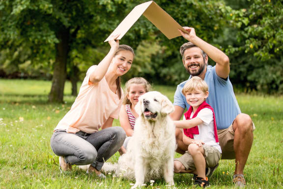 a family with their dog in a park holding up an inheritance sign